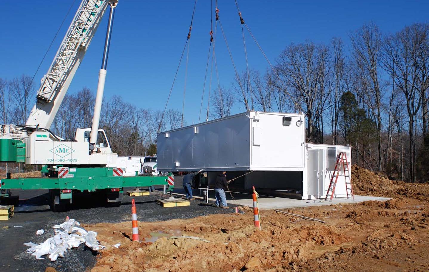 Two piece US Chemical Storage white modular being installed via crane during show on ground